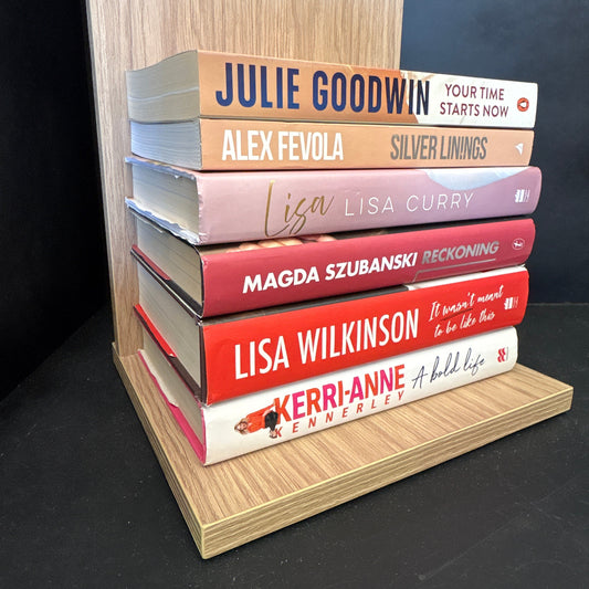 Row of books with visible authors' names on a wooden surface.