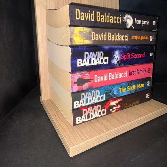 Set of books by David Baldacci on a wooden shelf