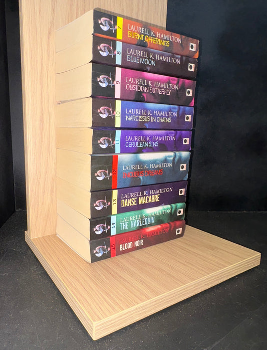 Set of books arranged on a wooden shelf against a dark background